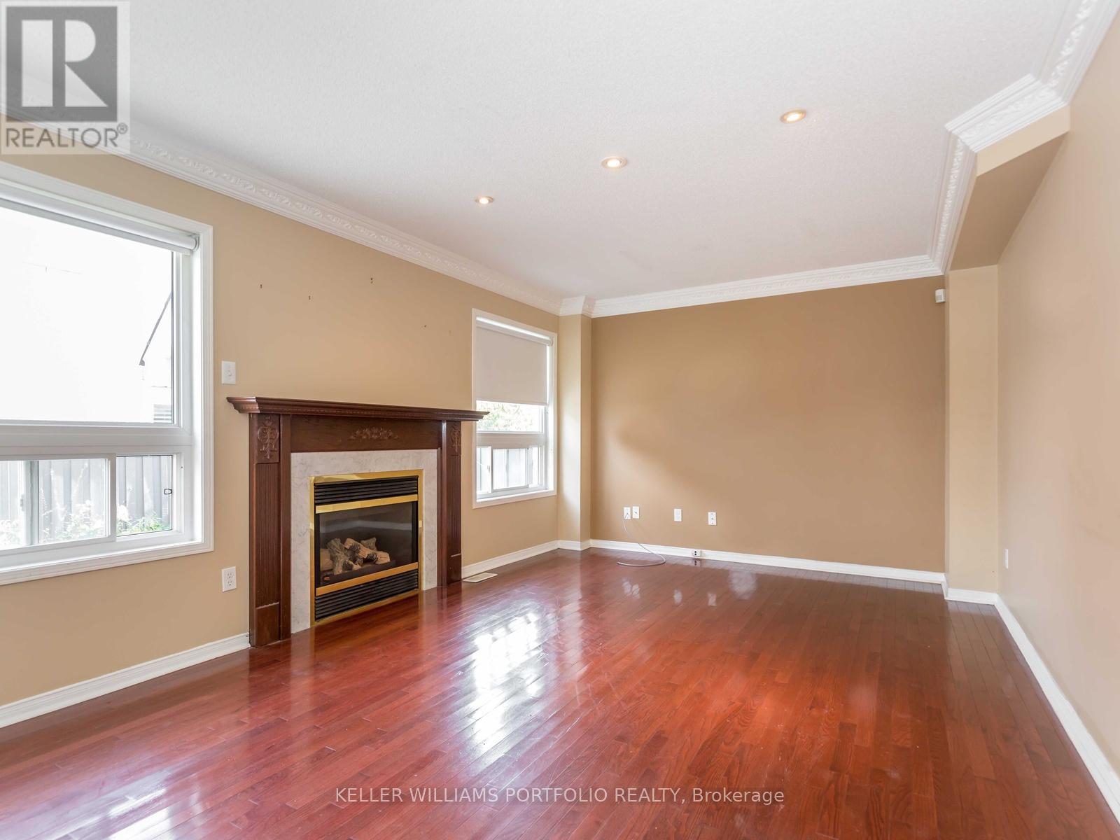 A spacious room with a fireplace and wood flooring.
