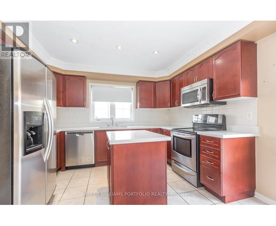 A kitchen with red cabinets and stainless steel appliances.