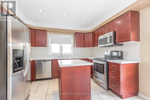 A kitchen with red cabinets and stainless steel appliances.