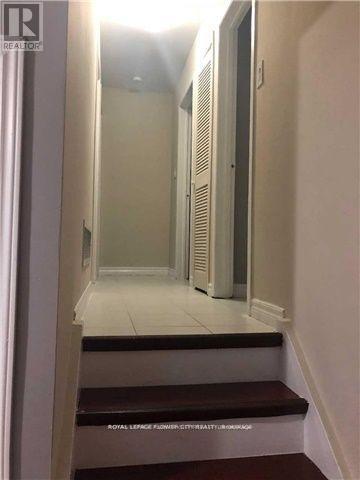 A hallway with a staircase leading to a door at the end.