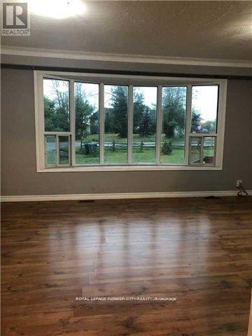 A room with a large window and wooden flooring.
