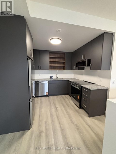 A modern kitchen with dark wood cabinets and stainless steel appliances.