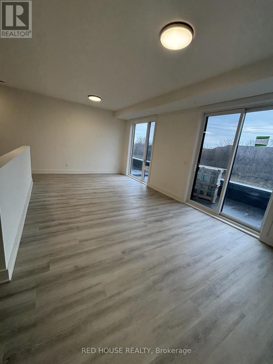 A spacious room with wooden flooring and large windows.