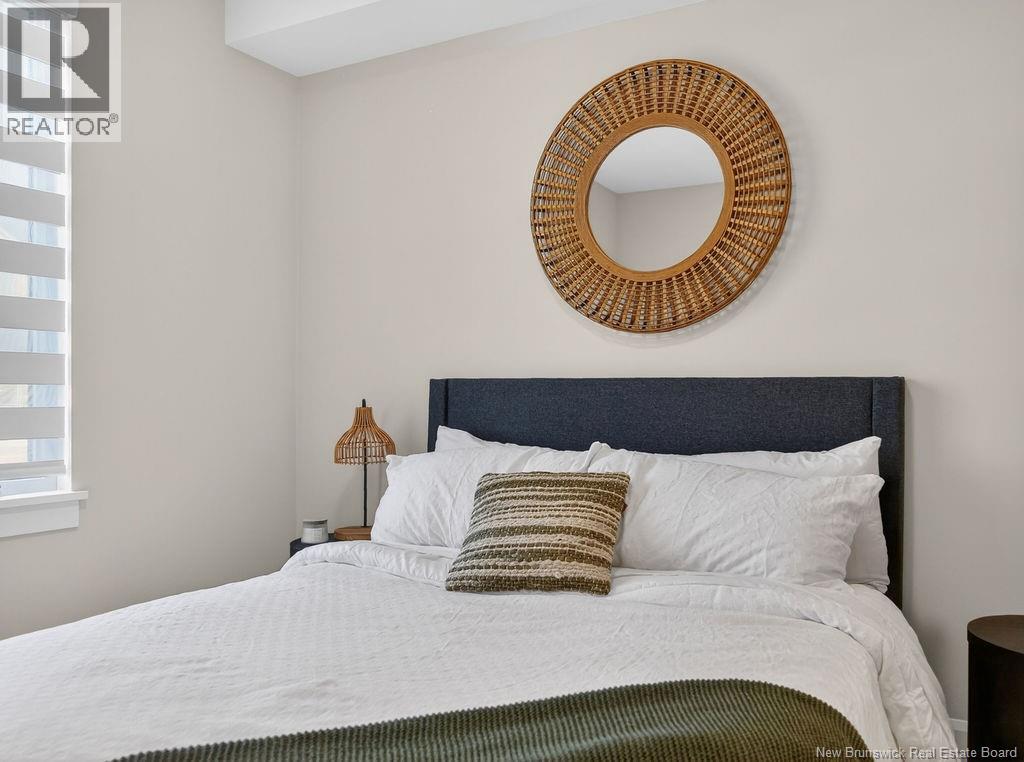 A bedroom with a white bed and a round mirror above it.