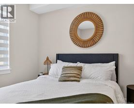 A bedroom with a white bed and a round mirror above it.