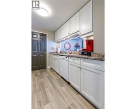 A kitchen with white cabinets and a wooden floor.