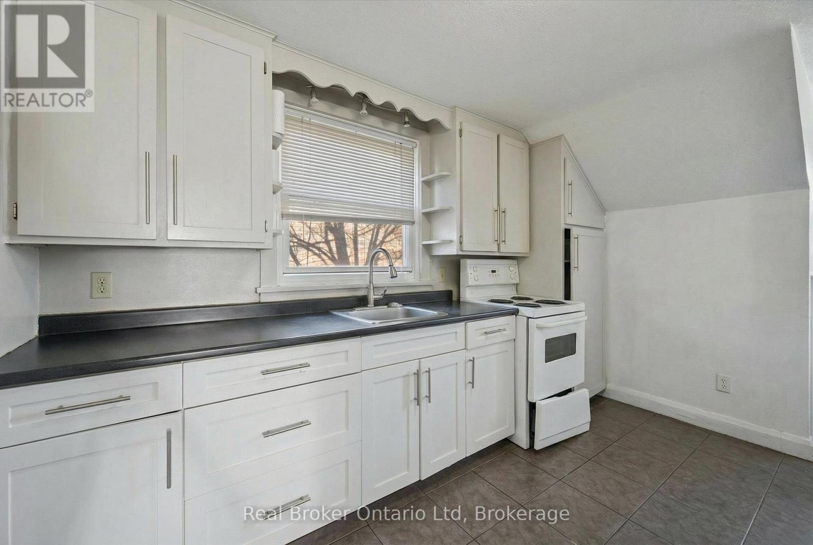 A kitchen with white cabinets and a black countertop.