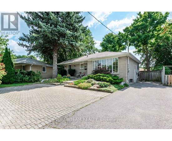 A house with a driveway and trees in front of it.