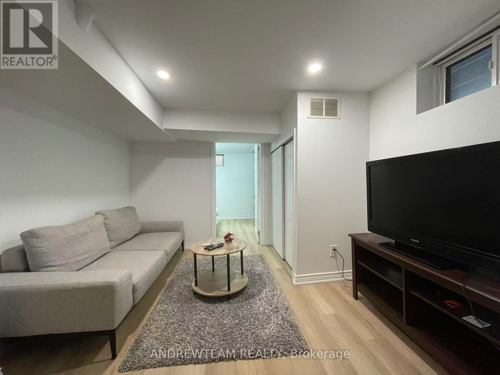 A living room with a grey couch, a coffee table, and a flat screen TV.
