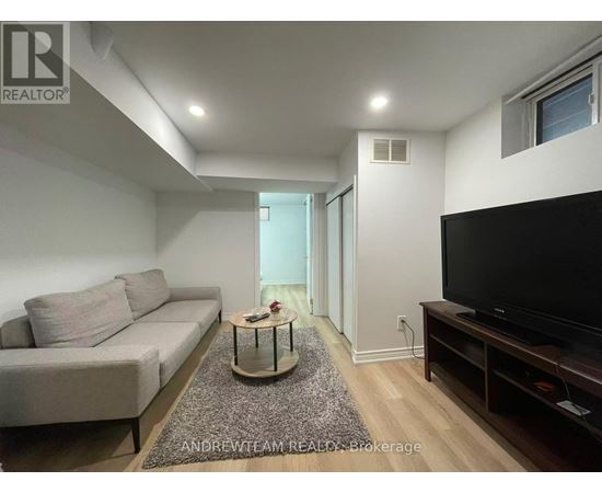 A living room with a grey couch, a coffee table, and a flat screen TV.