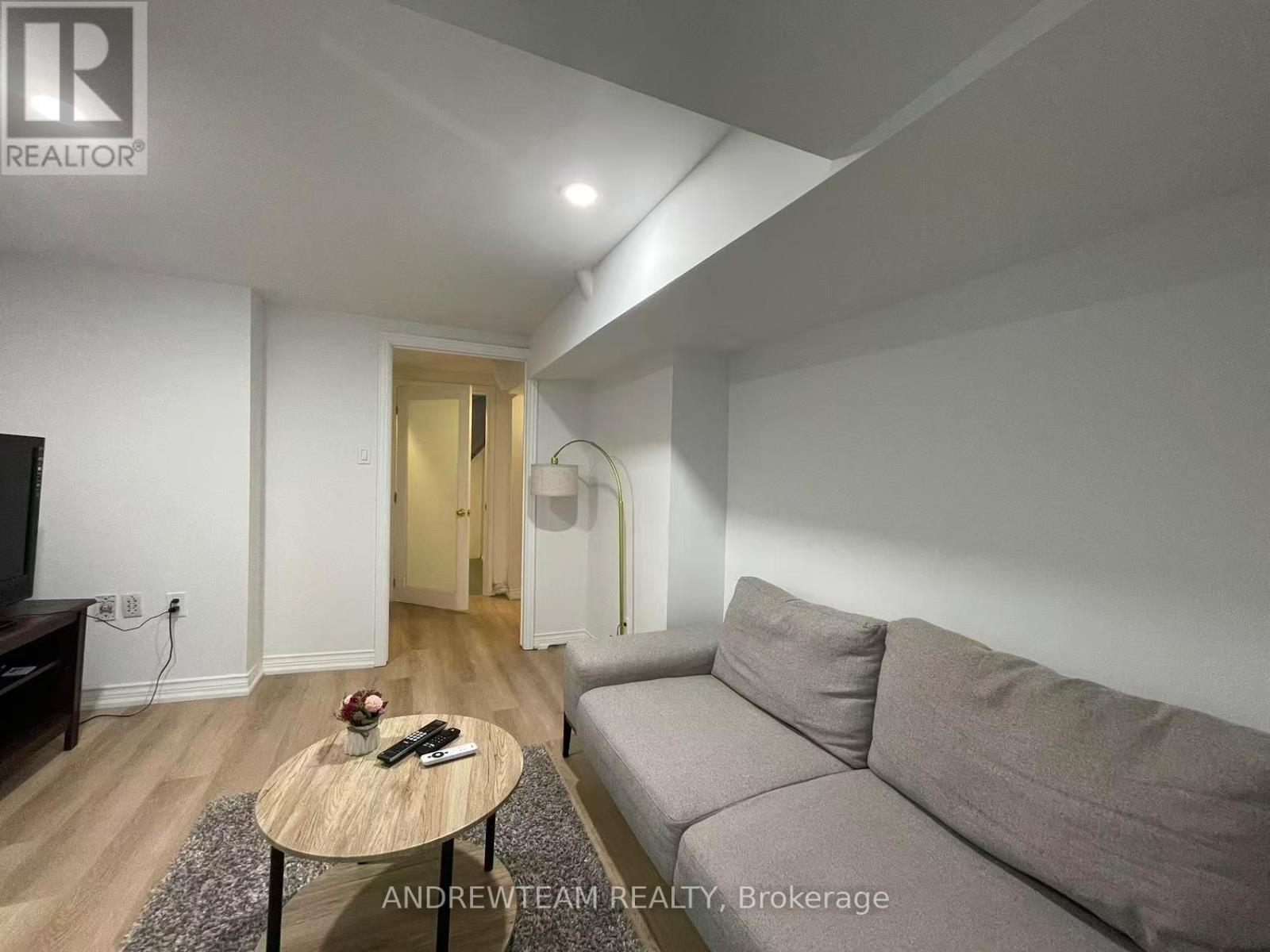 A living room with a grey couch, a wooden coffee table, and a flat screen TV.