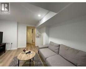 A living room with a grey couch, a wooden coffee table, and a flat screen TV.