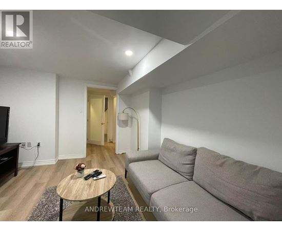 A living room with a grey couch, a wooden coffee table, and a flat screen TV.
