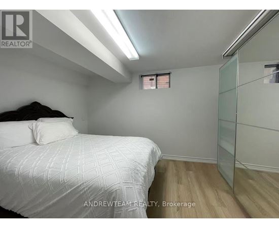 A bedroom with a bed, wooden floor, and a glass walled closet.