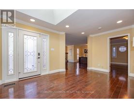 A spacious room with wood flooring and a skylight.
