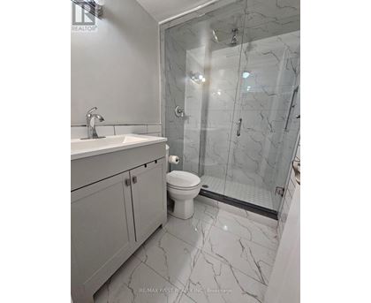 A bathroom with a marble floor and a walk-in shower.