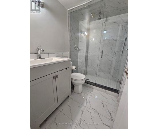 A bathroom with a marble floor and a walk-in shower.