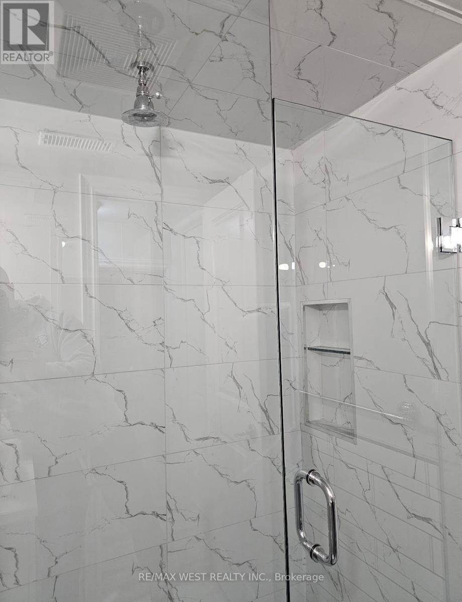 A white marble bathroom with a glass shower door.
