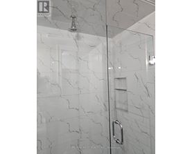 A white marble bathroom with a glass shower door.