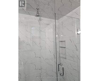 A white marble bathroom with a glass shower door.
