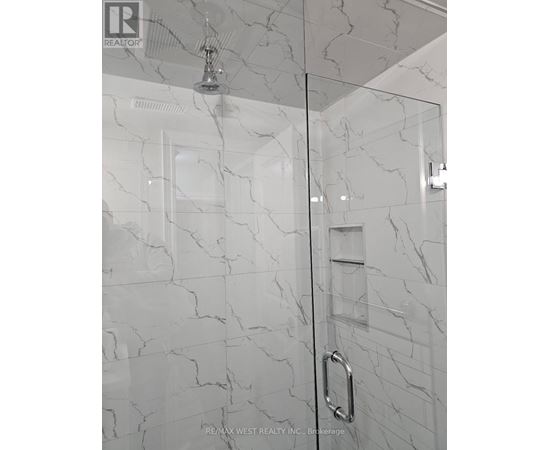 A white marble bathroom with a glass shower door.