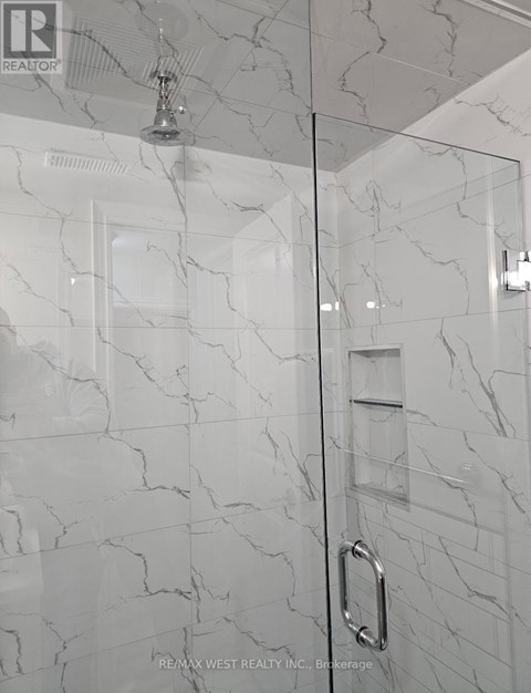 A white marble bathroom with a glass shower door.