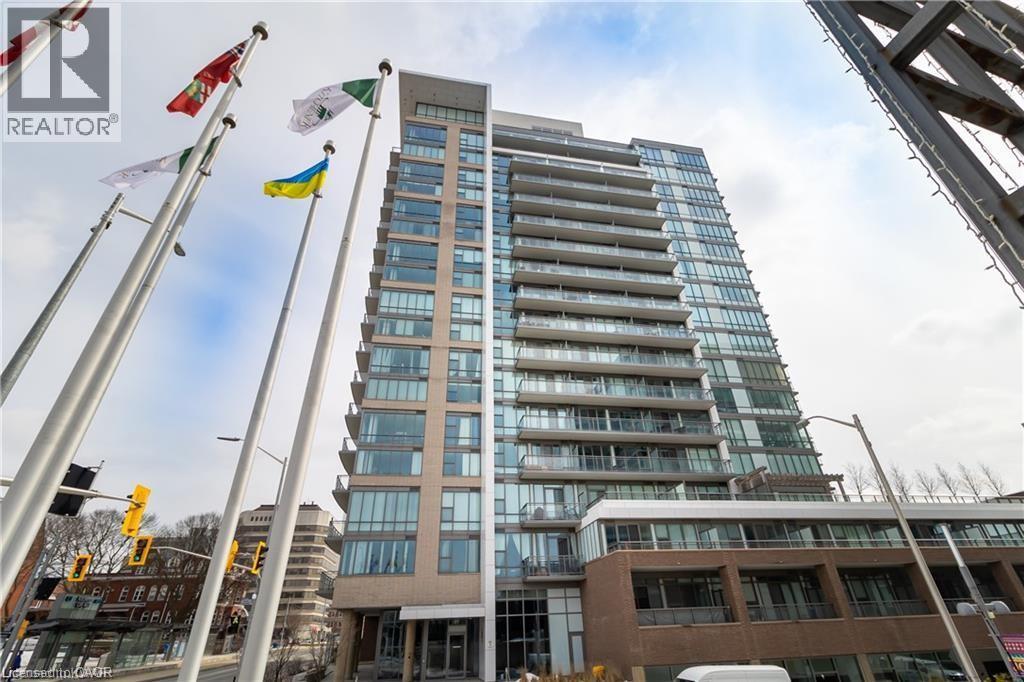 A tall building with many windows is seen with flags on poles in front of it.