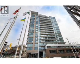 A tall building with many windows is seen with flags on poles in front of it.