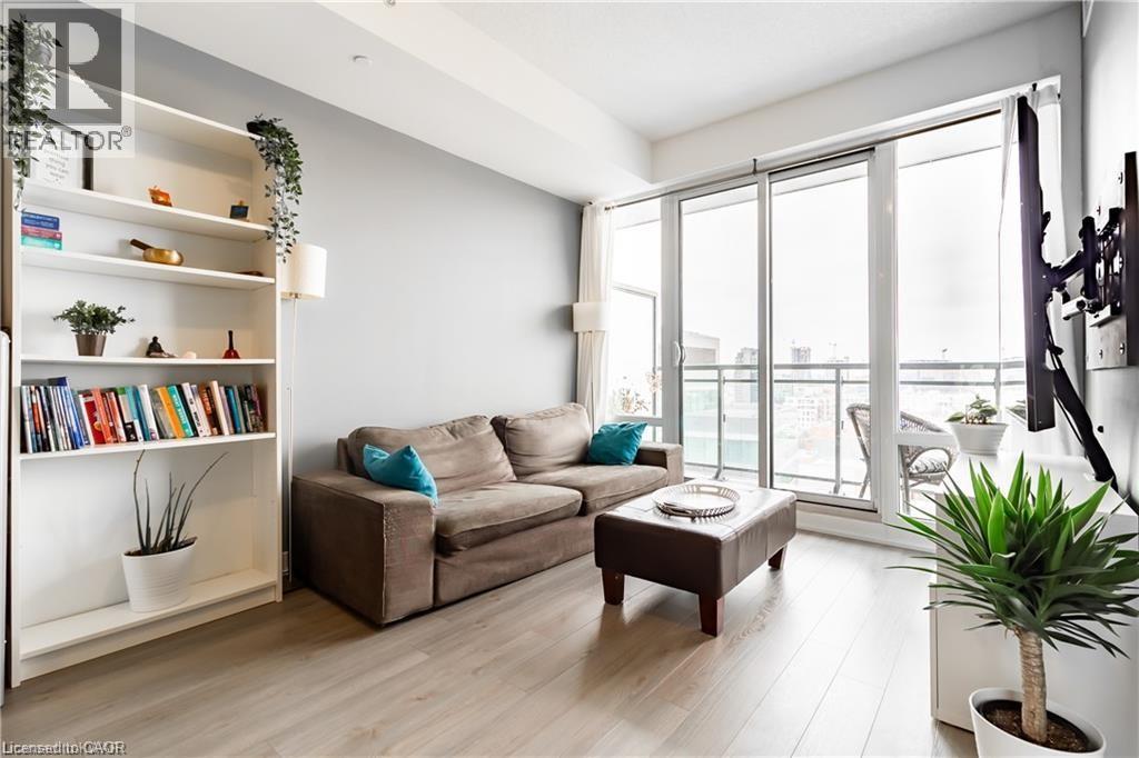 A living room with a couch, a coffee table, a bookshelf, and a plant.