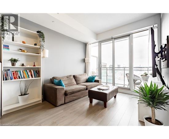 A living room with a couch, a coffee table, a bookshelf, and a plant.