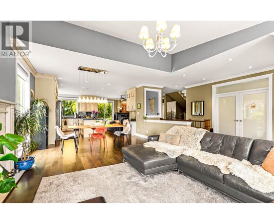 A well-lit living room with a grey sofa and a dining table.