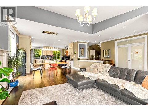 A well-lit living room with a grey sofa and a dining table.