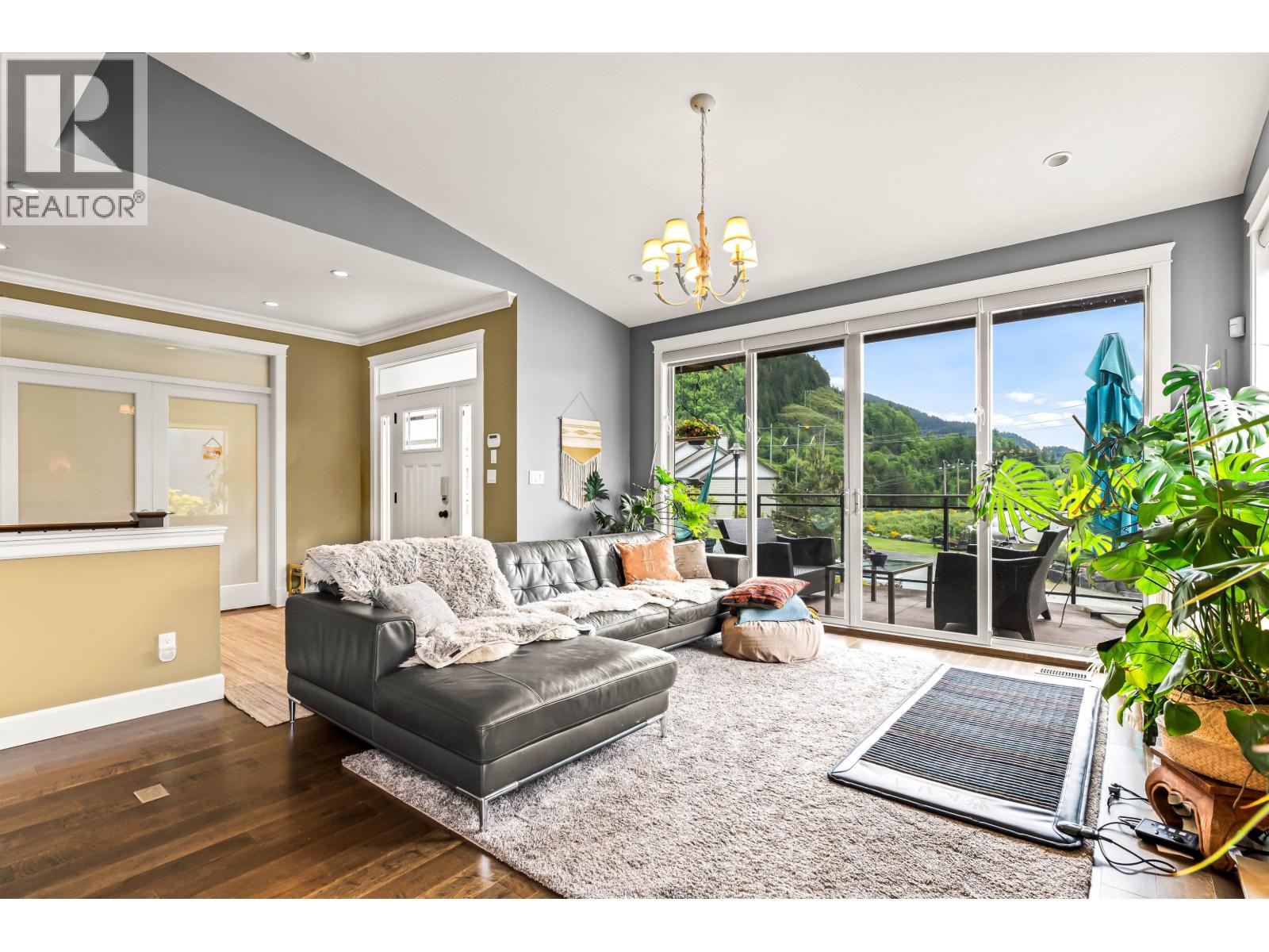 A living room with a grey couch and a chandelier.