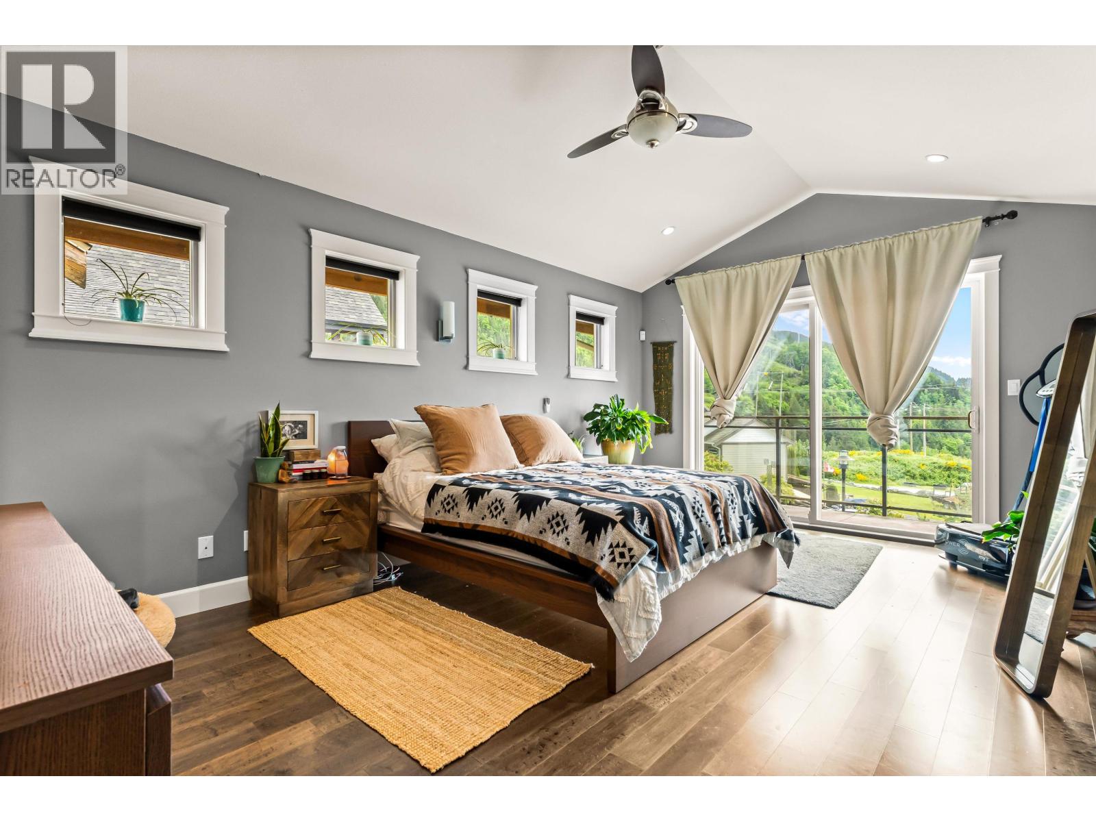 A bedroom with a large bed and a balcony overlooking a garden.