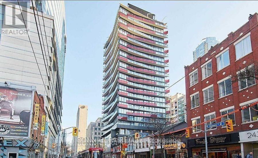 A tall, colorful building stands in the middle of a city street.