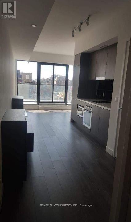 A spacious kitchen with dark wood floors and modern appliances.