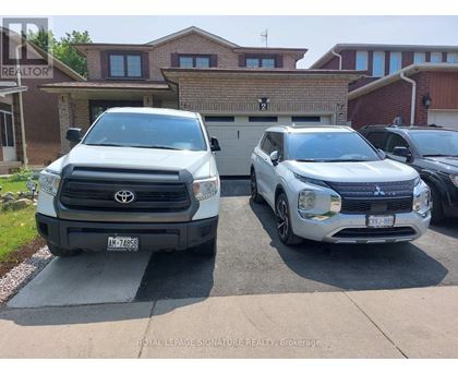 Two white vehicles are parked in front of a house.