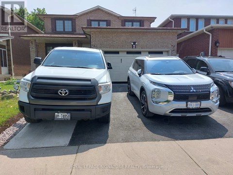 Two white vehicles are parked in front of a house.