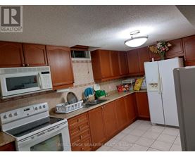 A kitchen with brown cabinets and white appliances.
