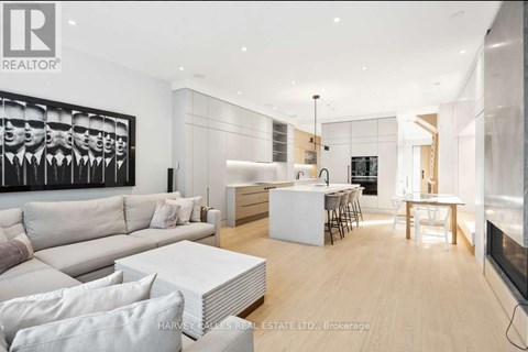 A modern living room with a large painting on the wall and a dining area in the background.