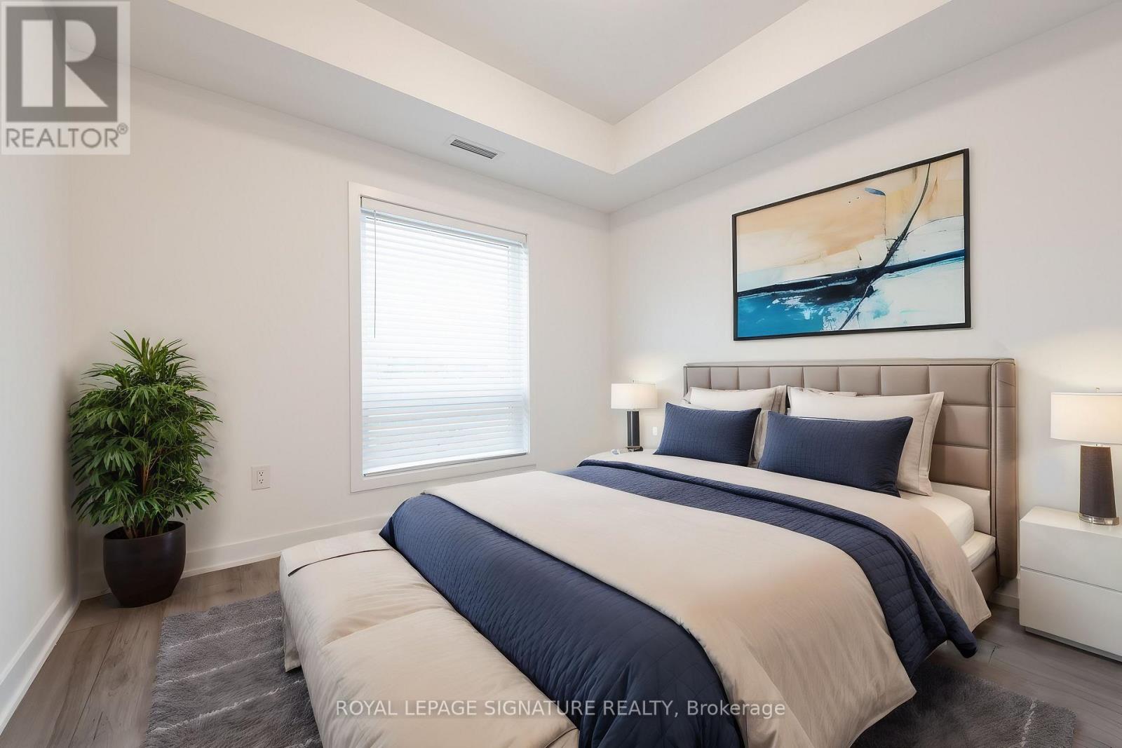 A bedroom with a large bed and a painting on the wall.