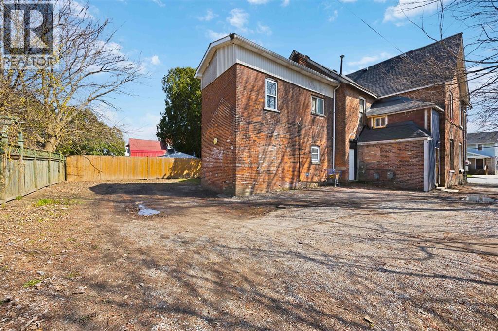 A large, old brick building sits in a lot with a dirt ground.