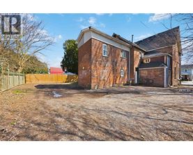 A large, old brick building sits in a lot with a dirt ground.