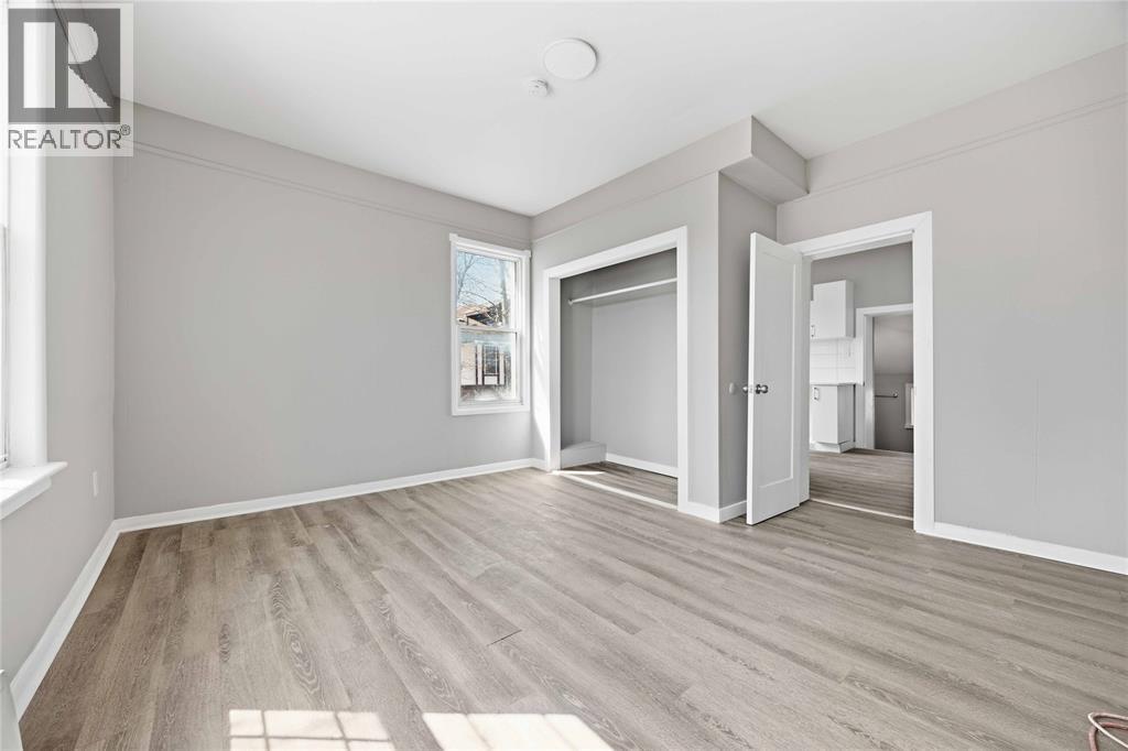 A spacious room with wooden flooring and a large window.