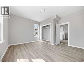 A spacious room with wooden flooring and a large window.