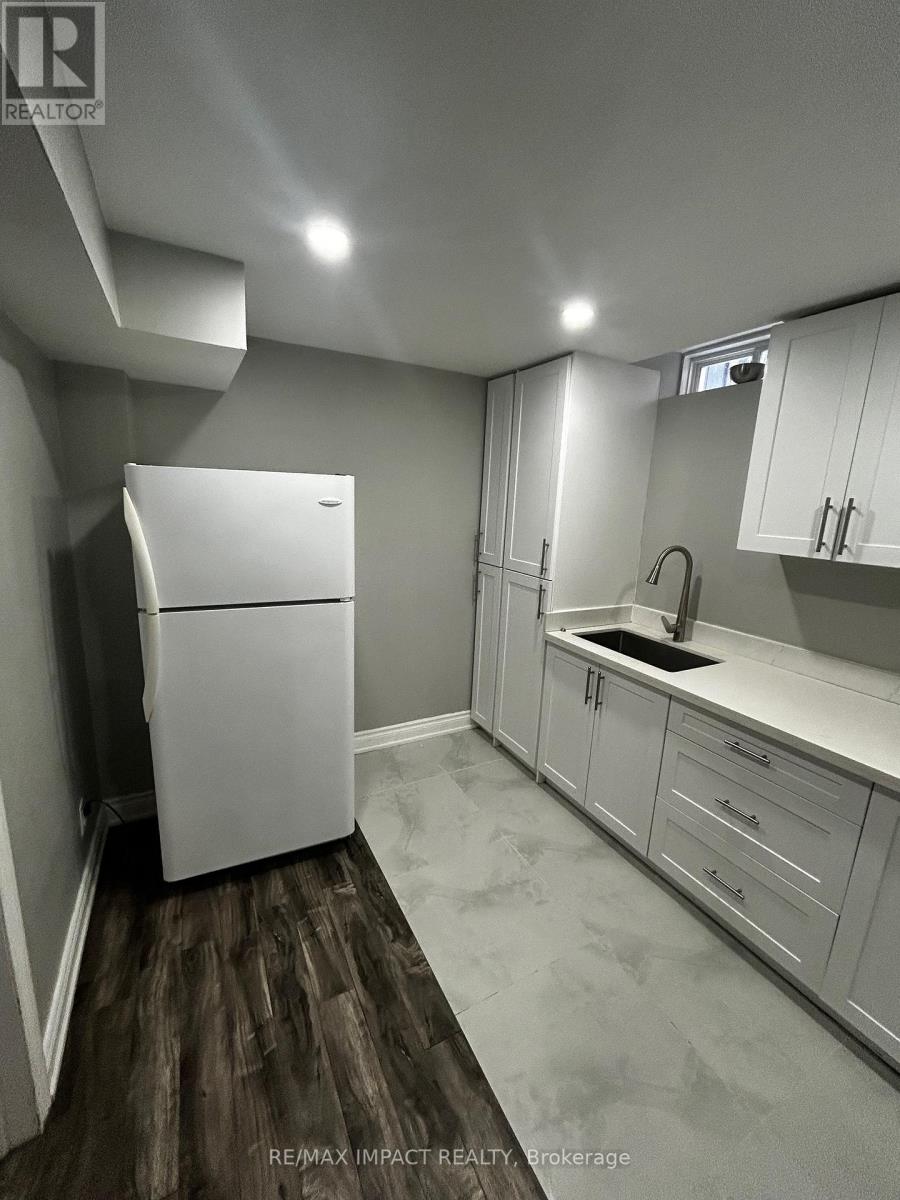 A white refrigerator in a kitchen with white cabinets and a wooden floor.