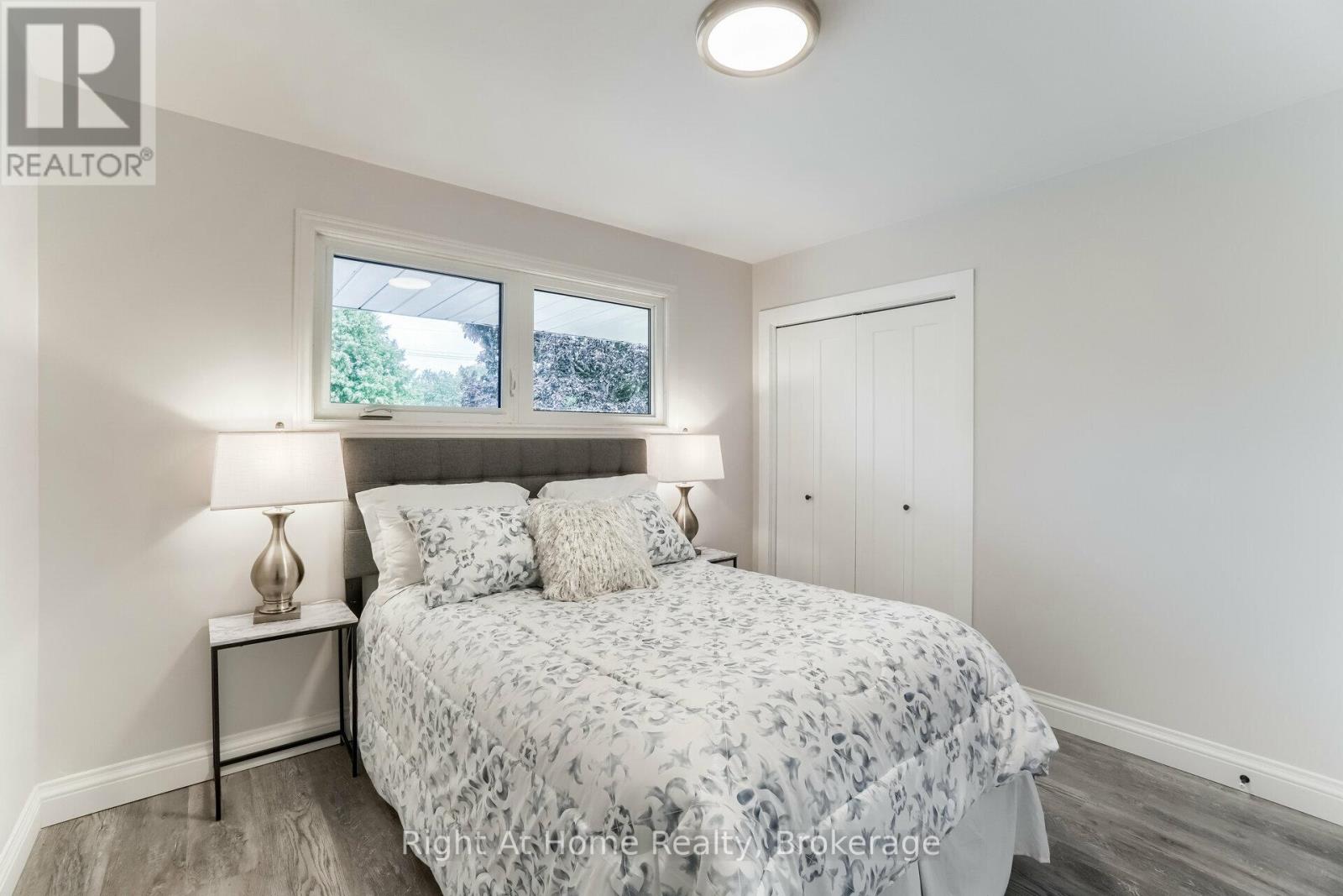 A bedroom with a bed, nightstand, and window.