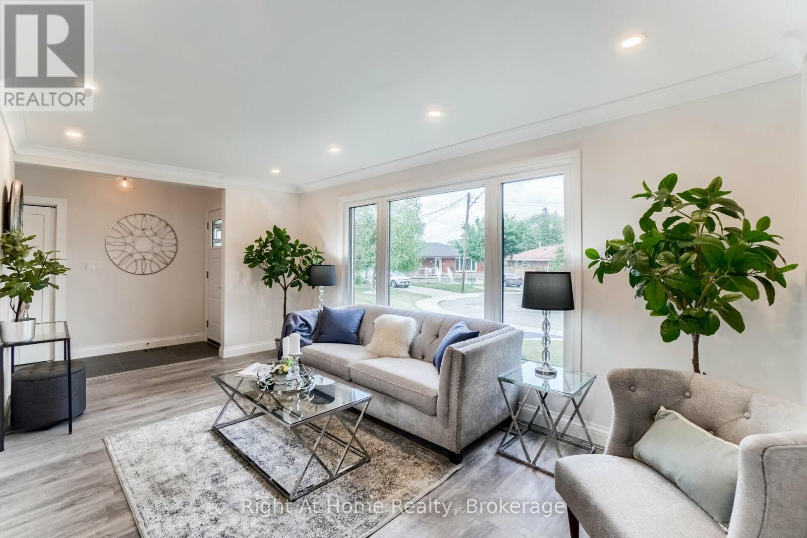 A well-lit living room with a glass coffee table and a grey sofa.