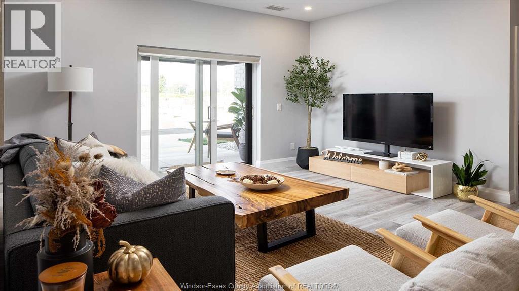 A living room with a grey couch, a wooden coffee table, a flat screen TV, and a plant.