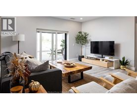 A living room with a grey couch, a wooden coffee table, a flat screen TV, and a plant.